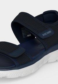 Σανδάλι Skechers σε ναυτικό μπλε με ρυθμιζόμενα λουράκια, υφή στην επάνω επιφάνεια, μαξιλαρωτή σόλα και λευκή σόλα με σχέδιο.