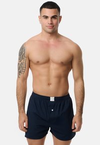 Marineblaue Baumwollshorts mit einem elastischen Taillenbund und einem Knopfdetail an der Vorderseite. Sie besitzen eine glatte Textur und ein minimalistisches Design.