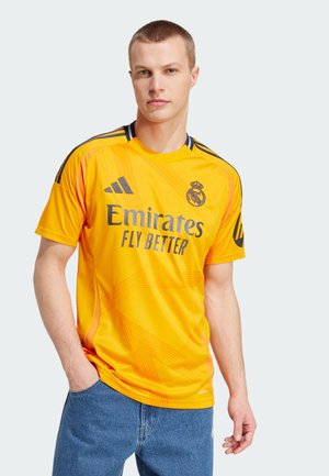 Maglia sportiva gialla realizzata in tessuto liscio, con scollo rotondo, dettagli neri e il logo "Emirates Fly Better" in lettere scure.