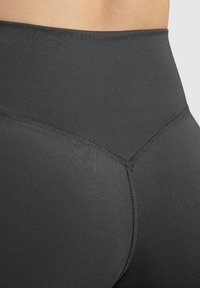 Leggings neri a vita alta con una texture liscia, caratterizzati da cuciture rinforzate e un design senza soluzione di continuità in vita e sul retro.