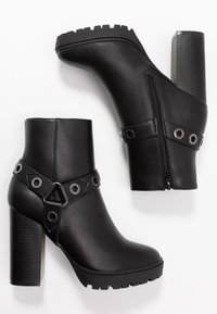 Botas de tobillo de imitación de cuero negro que presentan un tacón alto grueso, una plataforma texturizada, cierre lateral con cremallera y una correa decorativa con acentos metálicos.