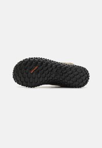 Suela de goma negra con patrones de tracción circulares, con la marca "Quantum Grip". La parte superior muestra un material marrón claro.