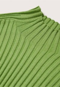 Gros plan sur un tissu en maille côtelée verte avec un poignet plié, montrant des motifs de points texturés verticaux et inclinés.