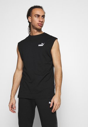 Canotta nera PUMA senza maniche, realizzata in cotone, con un logo bianco sul petto. Tessuto liscio con vestibilità comoda. Indossata con pantaloni neri.