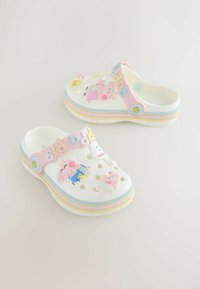 Hvide træsko med flere farverige figurdetaljer, inklusive Peppa Pig. Tekstureret rem med en pastelrosa og flerfarvet stribet bund.