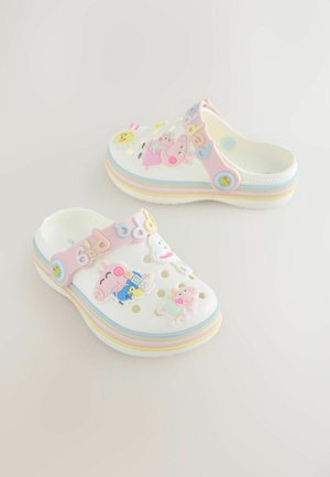 Valkoiset puukengät, joissa useita värikkäitä hahmotarroja, mukaan lukien Peppa Pig. Teksturoidulla remmillä, jossa vaaleanpunainen ja monivärinen raidoitettu pohja.