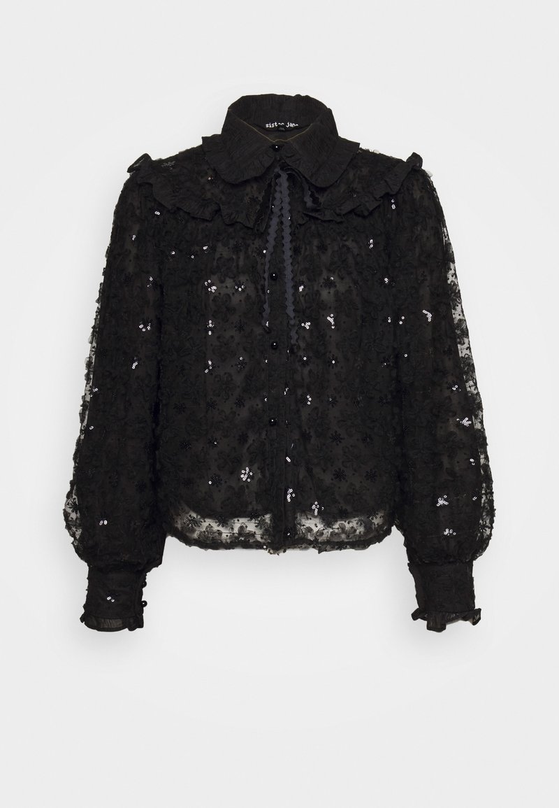 Blouse noire transparente en dentelle florale, ornements de sequins, grand col à volants, manches longues bouffantes et ouverture à boutons sur le devant.