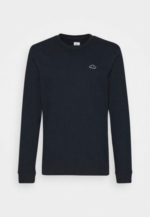 Sweat-shirt bleu marine à col rond, manches longues, avec un petit emblème de nuage blanc sur la partie supérieure gauche de la poitrine.