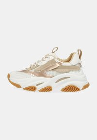 Baskets de sport blanches et dorées avec une tige en maille, semelle épaisse en cuir blanc et semelle extérieure en caoutchouc texturé beige. Présente un design à lacets et une languette.