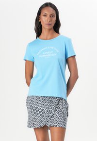 Camiseta de manga corta azul claro con texto blanco impreso en forma curva, combinada con una falda de rayas azul marino y blanca que presenta diseños geométricos.