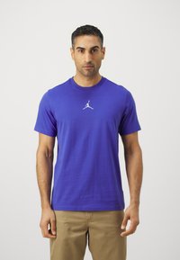 Camiseta de algodón de manga corta y cuello redondo en un vibrante color púrpura, con un logo Jumpman blanco centrado en el pecho.