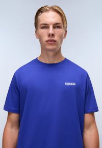 Kongeblå kortærmet t-shirt lavet af bomuld. Har et lille hvidt logo på brystet, rund halsudskæring og en afslappet pasform.