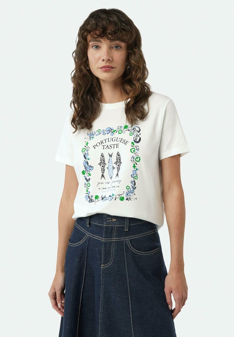 Witte katoenen T-shirt met een kleurrijk bloemenontwerp en tekst "Portugese Smaak," gecombineerd met een donkere spijkerrok en zichtbare knoopdetails.