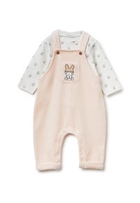 Różowe polarowe kombinezony z detalu kieszeni w formie królika, w zestawie z długim rękawem białej koszulki z małymi wzorami zwierząt. Miękka tekstura.