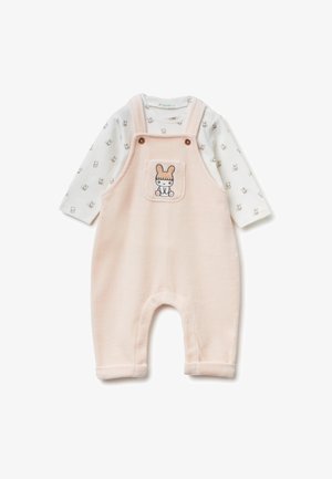 Rosa Fleece-Latzhose mit einem Hasentaschen-Detail, kombiniert mit einem langärmligen weißen Shirt mit kleinen Tiermustern. Weiche Textur.