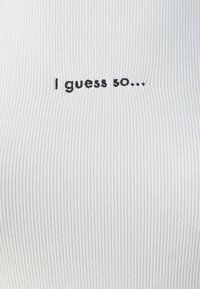 Bílá žebrovaná látka s černým vyšitým textem "Asi ano..." umístěným na středě povrchu.