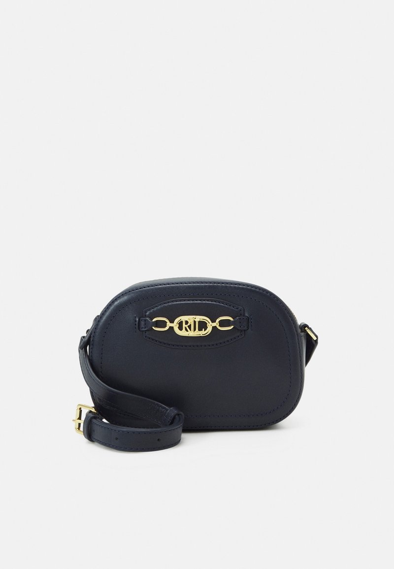 Navy leather crossbody bag with gold-tone hardware, rounded shape, decorative clasp, and adjustable strap. Smooth texture, minimal design.