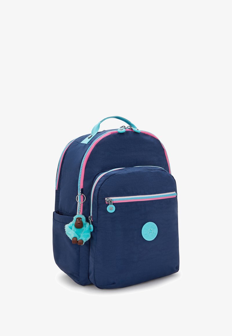 Zaino blu navy con cerniere rosa e turchesi, tasca frontale, portachiavi a forma di scimmietta in peluche e un patch circolare del marchio sulla parte anteriore.