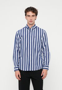 Μπλε και λευκή ριγέ πουκάμισο με κουμπιά, φτιαγμένο από βαμβάκι, που διαθέτει γιακά, μακριά μανίκια και μία τσέπη σ�το στήθος με μια μικρή λεπτομέρεια λογότυπου.