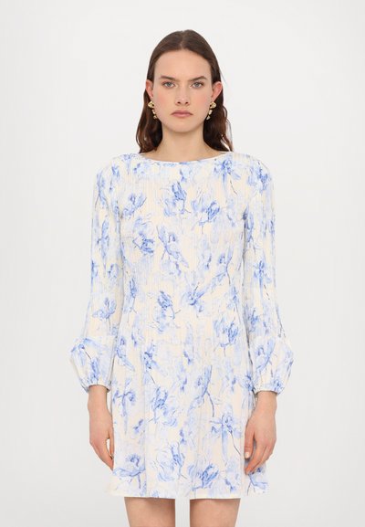 Robe crème avec des imprimés floraux bleu, manches bouffantes longues et encolure ronde. Tissu léger et texturé avec une silhouette évasée. Aucun autre détail visible.