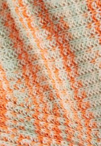 Háčkovaná tkanina v zelené, oranžové a krémové barvě, s texturovaným cikcak vzorem a kontrastními pruhy po celém povrchu.
