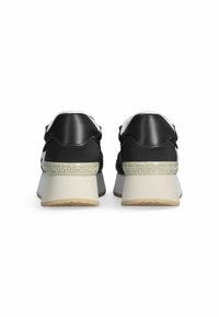 Zapatillas de cuero negro con un forro de piel de oveja blanca, con un tacón elevado que presenta un patrón decorativo crema en la parte trasera y una suela texturizada.