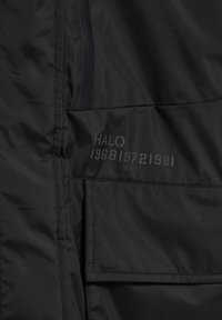 Czarna ocieplana kurtka z gładką fakturą i widoczną kieszenią na zamek. Na niej subtelnie wydrukowany napis "HALO 196819721981" w szarym kolorze.