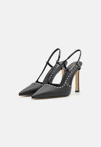 Décolleté slingback neri in pelle con punta affusolata, caratterizzati da cuciture bianche lungo i bordi e un tacco alto e sottile.