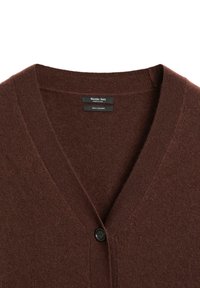 Brun kashmirtröja med V-halsdesign och en svart knäppning, med märkesetiketter inuti halsringningen.