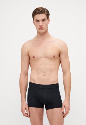 Schwarze Boxershorts aus einem glatten Material. Hervorgerufen durch einen breiten Bund, der mit dem Wort "BORN" geprägt ist. Figurbetontes Design mit minimalen Nähten.