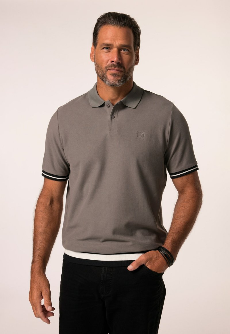 Polo grigio a maniche corte, con dettagli a strisce bianche e nere sulle maniche, texture a costine, abbinato a jeans scuri.