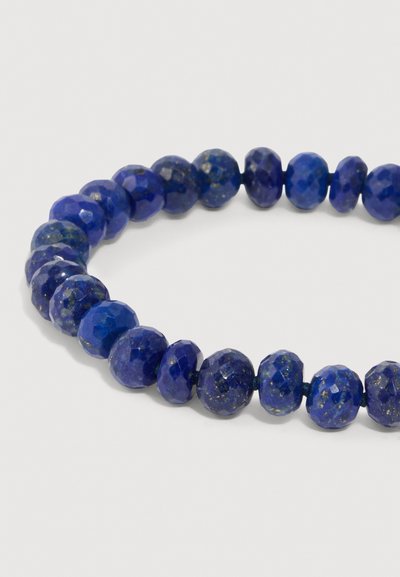 Pulsera de lapislázuli azul con cuentas redondas y ovaladas facetadas, que muestran ricos tonos azules y destellos dorados. Textura suave y acabado pulido.
