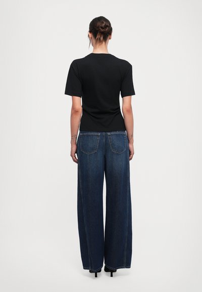 Black short-sleeve t-shirt paired with high-waisted, wide-leg dark denim jeans featuring two back pockets and a clean finish.
