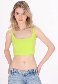 Neon groene cropped tanktop met een ronde hals, gemaakt van ribgebreide stof. Draagt met lichtblauwe denim shorts.