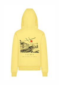 Yellow hooded sweatshirt featuring a graphic print of a train track scene with buildings and a red sun. Text reads "ESCAP3 AND DISCOVER THE WORLD."
