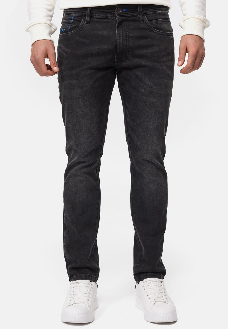 Svart denimjeans med smal passform, med subtil blekning, blå sömmar och stylade med vita sneakers.