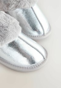Shiny silver slippers with a crackled texture, featuring soft grey faux fur trim and a white rubber sole.