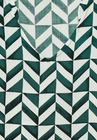 Tessuto stampato con un design geometrico che presenta forme triangolari alternate di colore verde scuro e bianco, texture liscia e scollatura a barca.