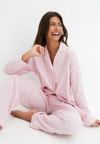 Set di pigiama a righe rosa e bianche, composto da una camicia con bottoni e pantaloni larghi con polsini. Tessuto morbido e vestibilità comoda.