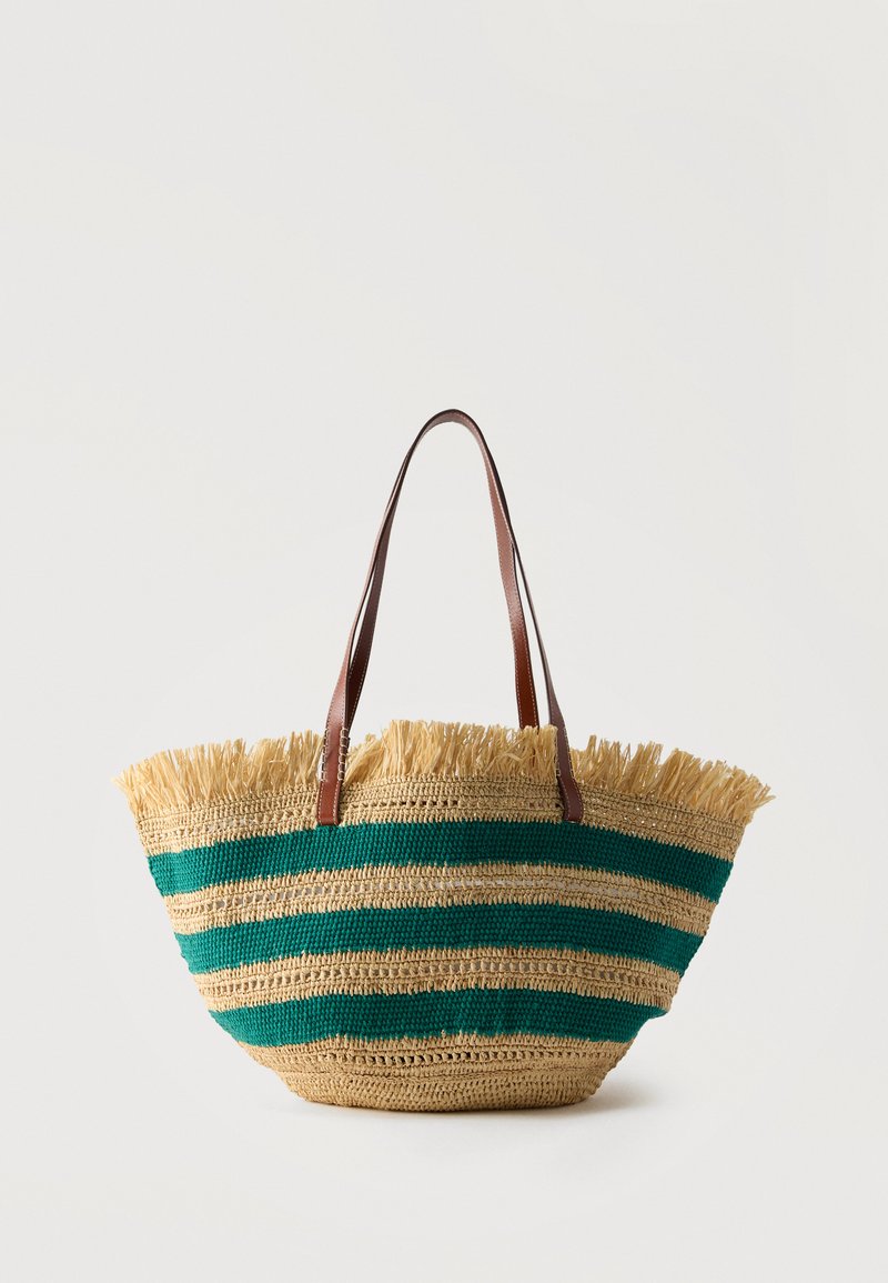Sac cabas en paille tressée avec des rayures horizontales vertes, bordure à franges en haut, et deux anses d'épaule en cuir marron.