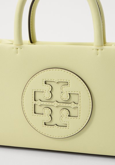 Bolsa de mão em pele amarela com alças arredondadas e um logótipo circular. A textura suave e os detalhes de costura discretos realçam o design.