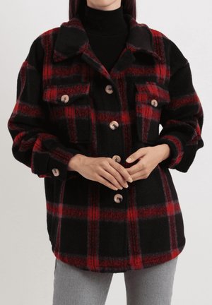 Chaqueta sobredimensionada a cuadros negros y rojos hecha de lana, con cuello, dos bolsillos en el pecho y botones de madera, que presenta un ajuste relajado y mangas enrolladas.