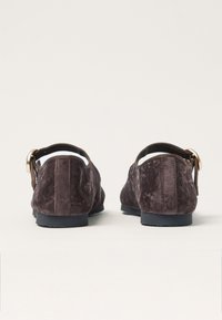 Scarpe in suede marrone con profilo basso, dotate di punta rotonda e una fascia in tessuto con una fibbia metallica sul retro per una vestibilità sicura.