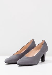 Chaussures à talons hauts en daim gris avec un bout rond et un talon bloc de hauteur moyenne. Texture lisse avec une découpe en V profonde à l'avant.
