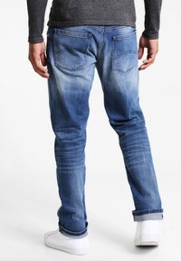 Ljusblå denimjeans med en avsmalnande passform, blekningsmönster och två bakfickor. Bärs med vita sneakers och en grå topp.