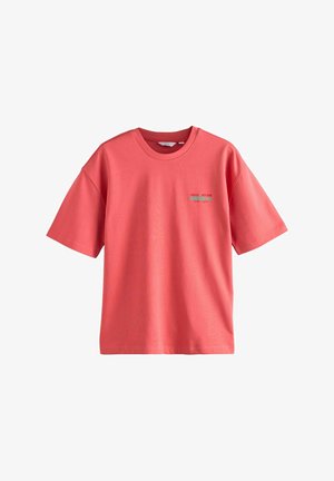 Koralvärviline puuvillane T-särk lühikeste varrukatega, ümmarguse kaelusega ja vasakul pool rohelise graafilise tekstiga, omades mugavat lõiget ja siledat tekstuuri.