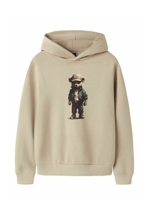 Felpa con cappuccio beige con grafica di un orso che indossa un cappello, giacca, pantaloni e sneakers in piedi al centro della parte frontale.