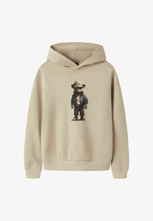 Beige hoodie met een afbeelding van een beer die een pet, jas, broek en sneakers draagt, gecentreerd op de voorkant.