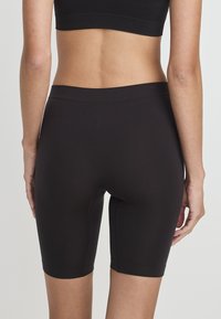 Czarne spodenki rowerowe o gładkiej strukturze, z dopasowanym krojem sięgającym do połowy uda oraz elastycznym pasem dla komfortu.
