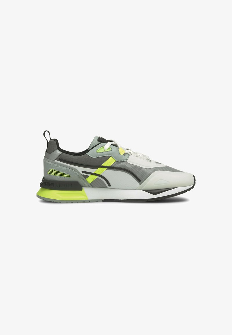 Chaussure de sport légère en gris, blanc et noir avec des accents jaune néon. Comprend des panneaux en mesh, une semelle extérieure texturée et un talon rembourré.